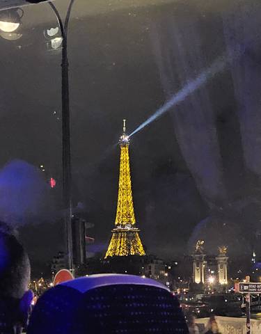The Eiffel Tower illuminated at night with a beam of light.