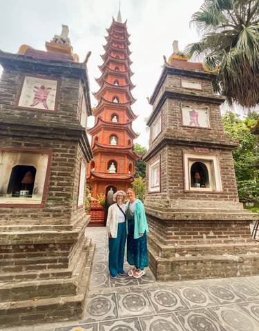Two women posing in front of an ornate pagoda.