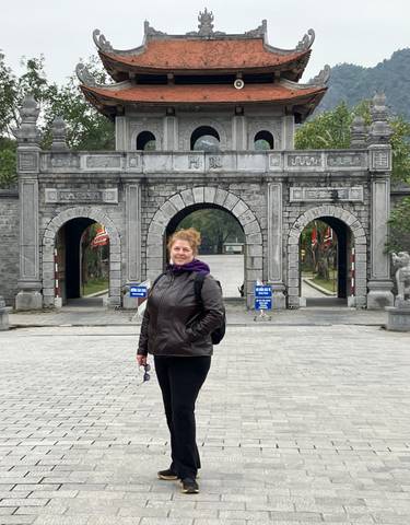 Person standing in front of a traditional Vietnamese gate.