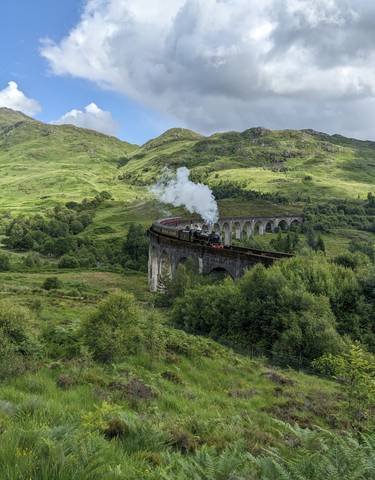 Steam train crossing a historic viaduct.