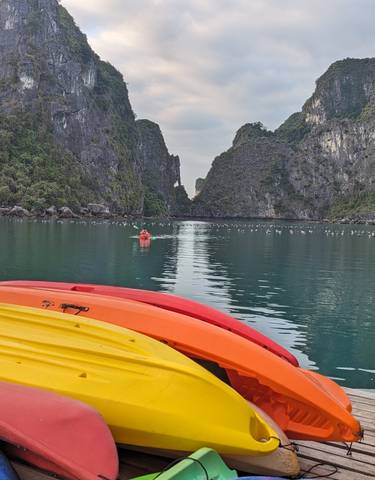 Colorful kayaks lined up with scenic cliffs over the water.