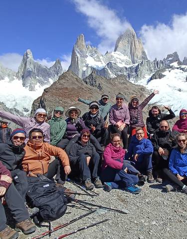 Group of trekkers posing in front of snow-capped mountains.