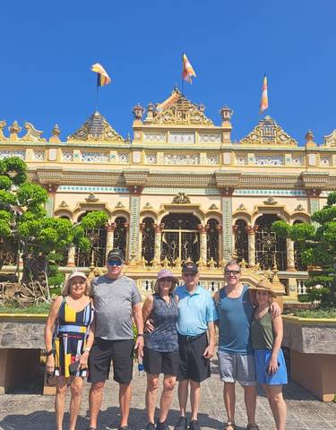 Tourists posing in front of a decorative temple.