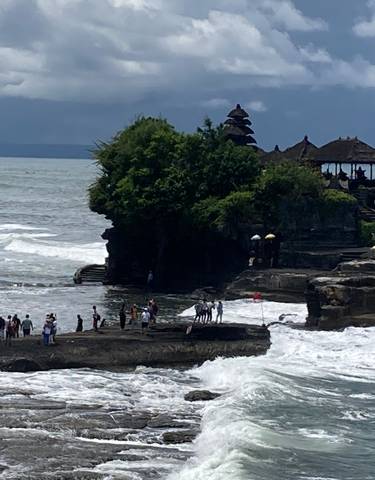 Temple on a rocky coastline with crashing waves.