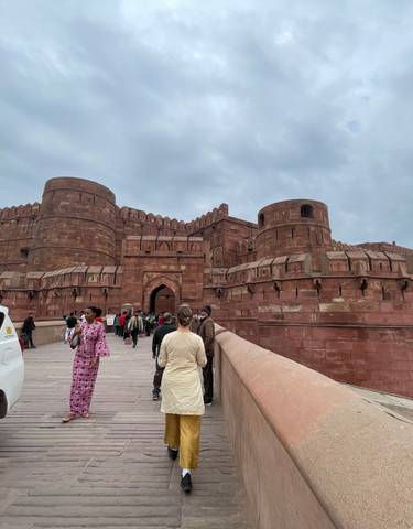 People entering a large, historic fort structure.