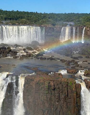 Wide view of Iguazu Falls with a rainbow.