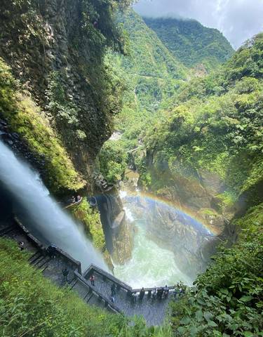 Waterfall in a lush canyon with a rainbow.
