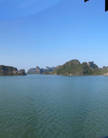 Halong Bay with scattered islands on a sunny day.