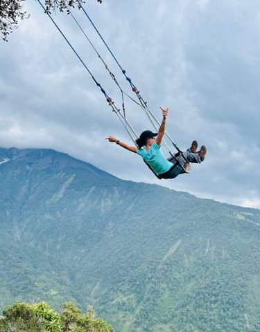 A person on a swing with a breathtaking mountain view.