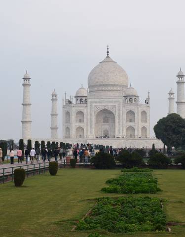 The Taj Mahal in Agra with a group of people walking in the foreground.
