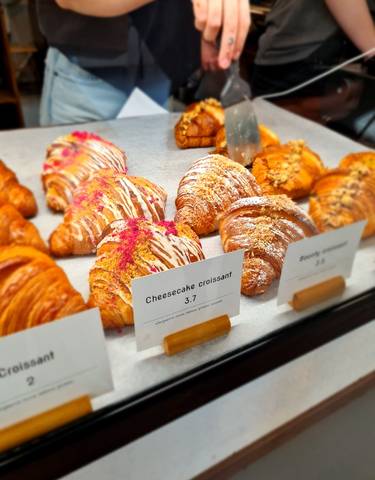 Display of various croissants in a bakery with price tags.