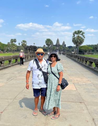 Couple posing on a stone pathway with Angkor Wat in the background.
