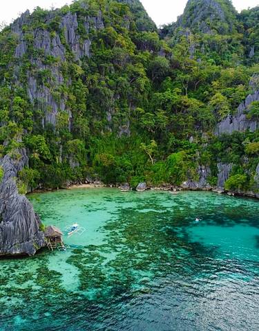 Aerial view of a tropical lagoon with turquoise waters and lush cliffs.
