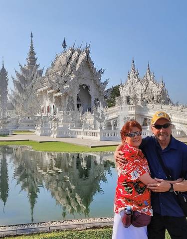Couple in front of a white temple with reflection in water.