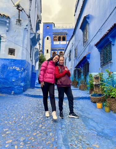 Two women standing in a blue-colored street.