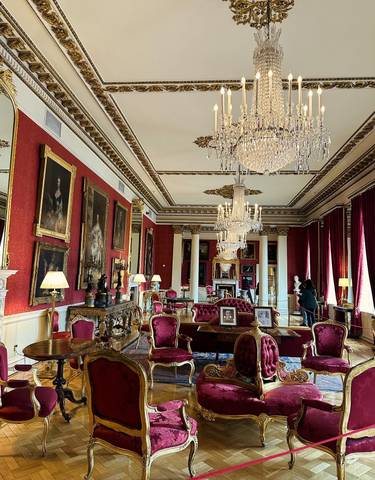 Luxurious interior of a historic building with chandeliers and paintings.