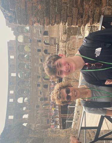 Two people posing in front of the Colosseum.
