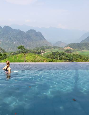 Person swimming in infinity pool with mountain view in the background.