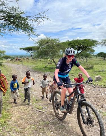 Cyclist and children on a dirt road with bicycles in rural landscape.
