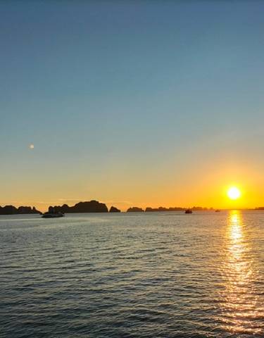 A scenic sunset view over a bay with boats visible in the water.