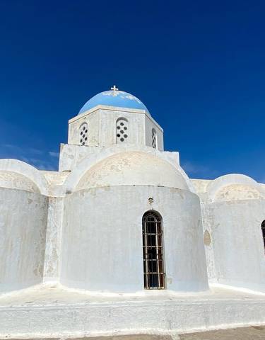 Whitewashed domed church with a blue dome under a clear sky.