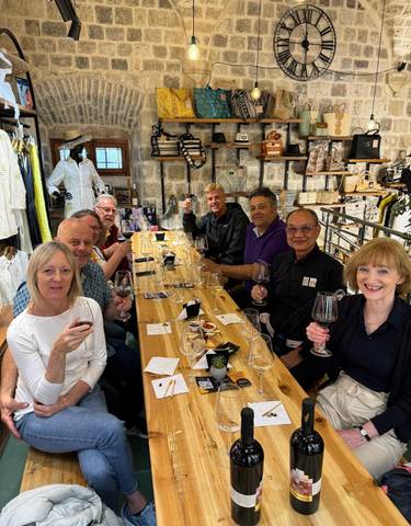 Group enjoying wine at a long table inside.