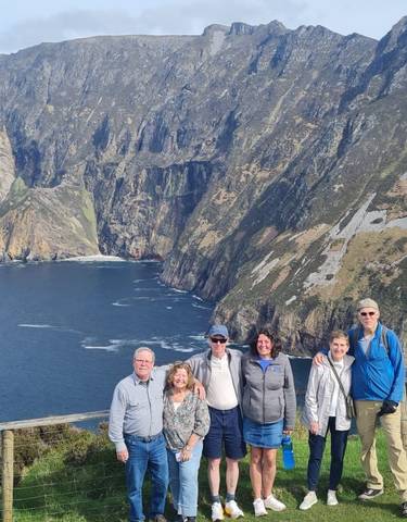 Group of people with a scenic coastal cliff background.
