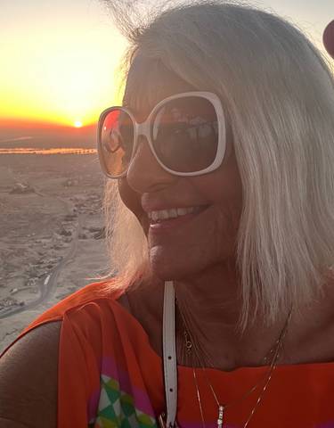 Woman enjoying a hot air balloon ride at sunset with expansive landscape views.