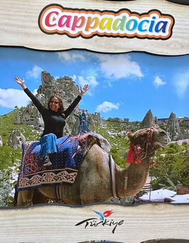 Woman joyfully riding a camel with rock formations in the background.