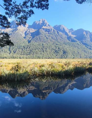 A mountain range reflected in a calm body of water.