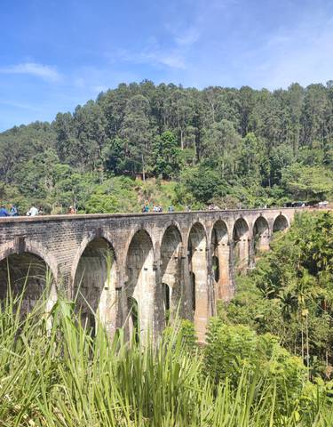 Nine Arch Bridge with people walking on it surrounded by greenery.