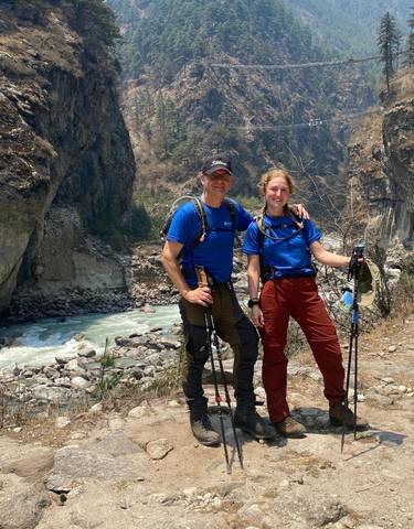 Two hikers posing with mountain rapids in the background.