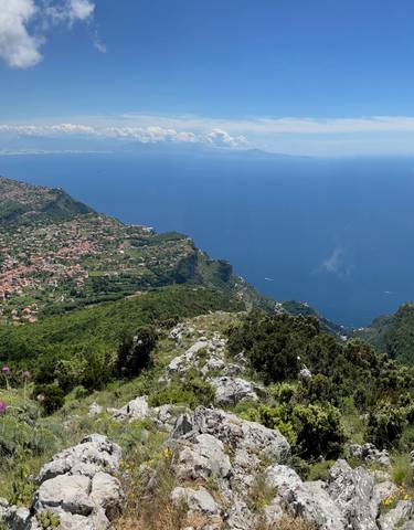 Panoramic view of mountains and a distant coastline with a cloudy sky.