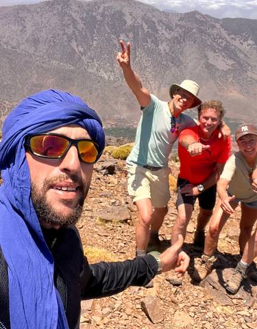 People posing on a rocky mountain landscape with a scenic view.