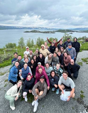 Group of tourists posing with a fjord and islands visible in the background.