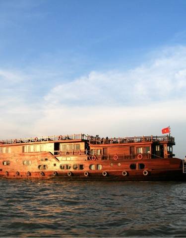 Large wooden cruise boat on a river at sunset.