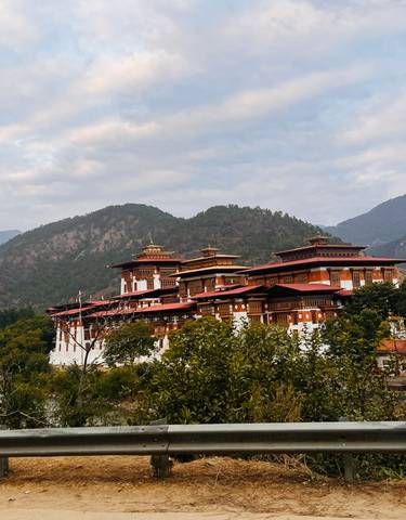 Large monastery surrounded by mountains and trees.