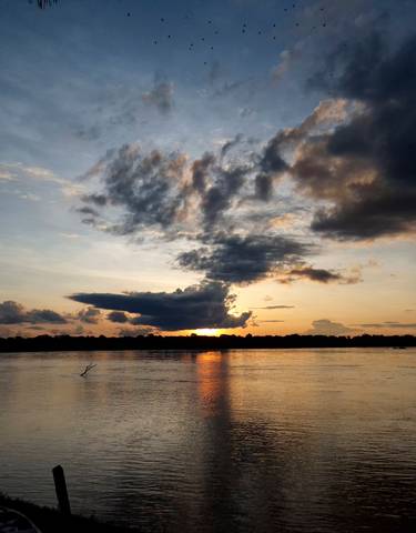Sunset view over a calm river with dramatic clouds.