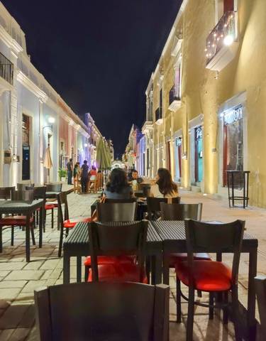 Nighttime street cafe with people dining outdoors.
