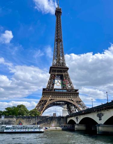 Eiffel Tower with Olympic rings against a blue sky.