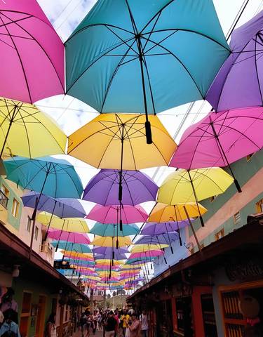 Street with colorful umbrellas hanging overhead.