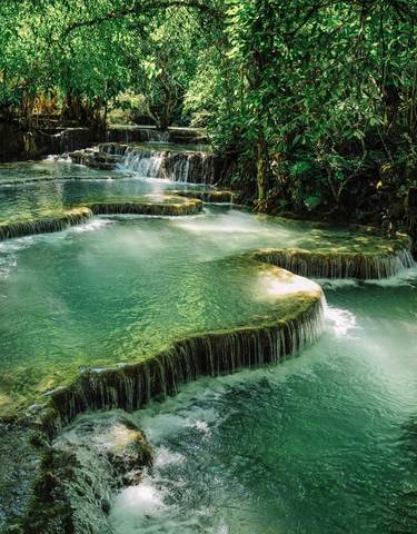 Series of terraced waterfalls in a lush forest setting.