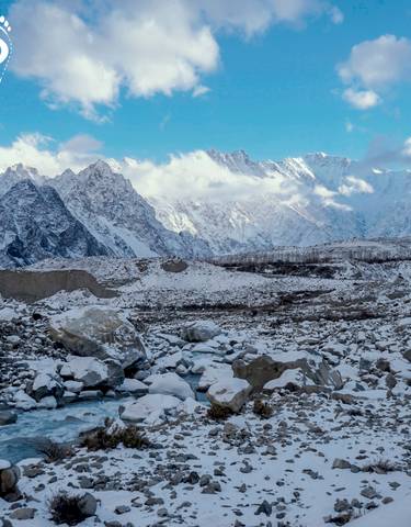 Snow-capped mountain range with clouds.