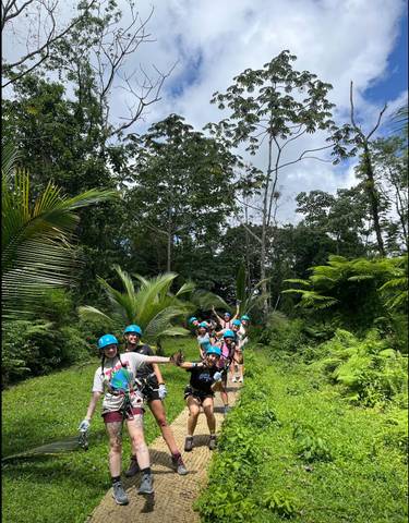Group posing with helmets and harnesses in a jungle setting.