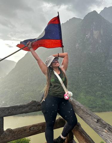 Person holding a flag atop a mountain with scenic views.