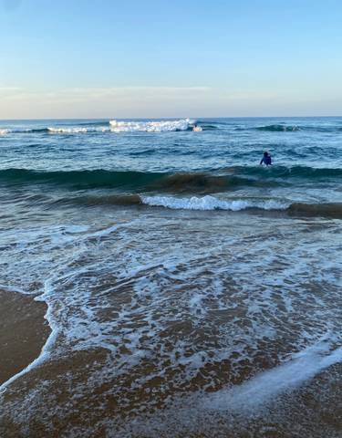 Person in the ocean with waves approaching the shore.