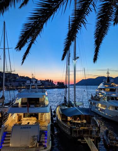 Yachts moored in a marina during sunset.