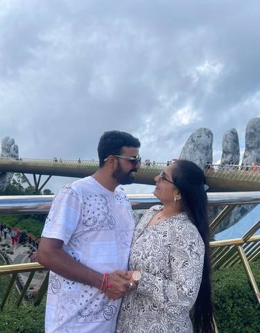 Couple posing on a bridge with giant stone hands.