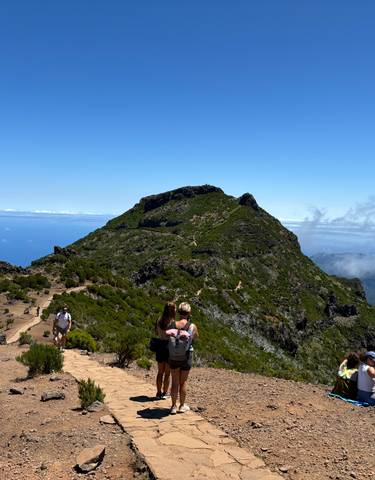 People hiking on a mountain trail with ocean view.