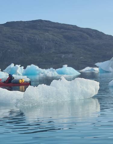 Kayakers paddling near iceberg in a serene setting.